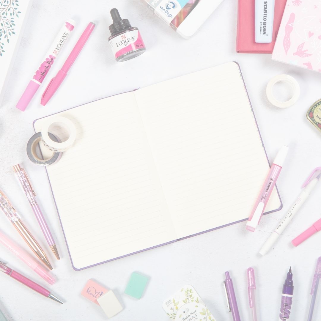 Assorted stationery items including pens, markers, and a notebook on a white surface.