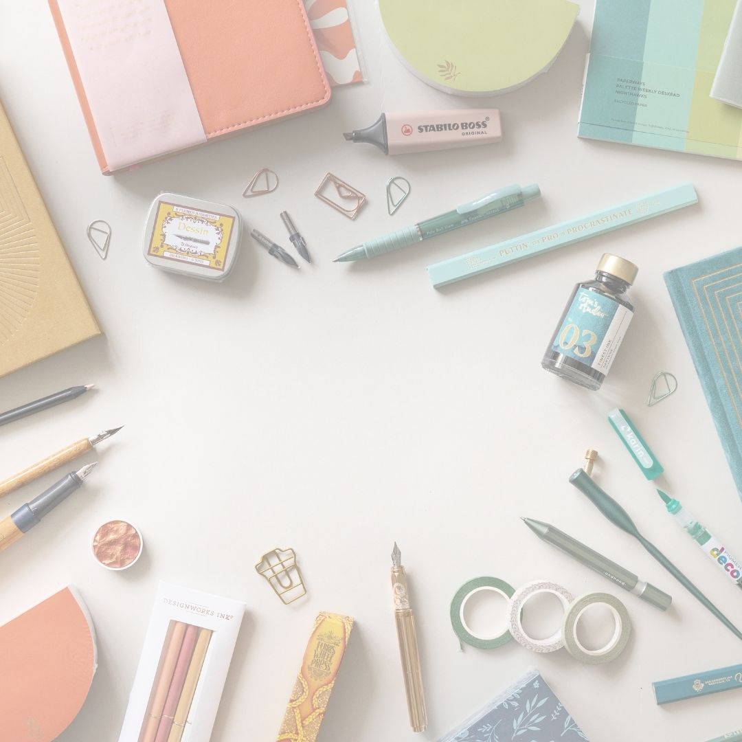 Assorted stationery items including pens, notebooks, and markers on a light surface.