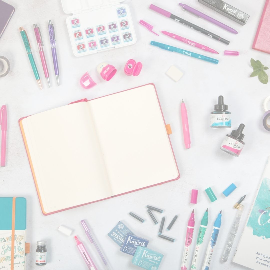 Assorted stationery items including pens, markers, and a notebook on a white surface.