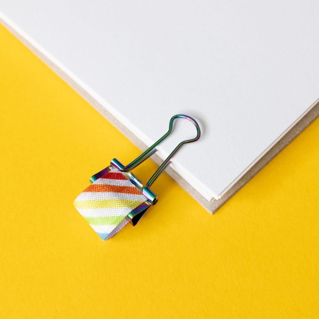 Colourful striped pen clip on a white book with a yellow background
