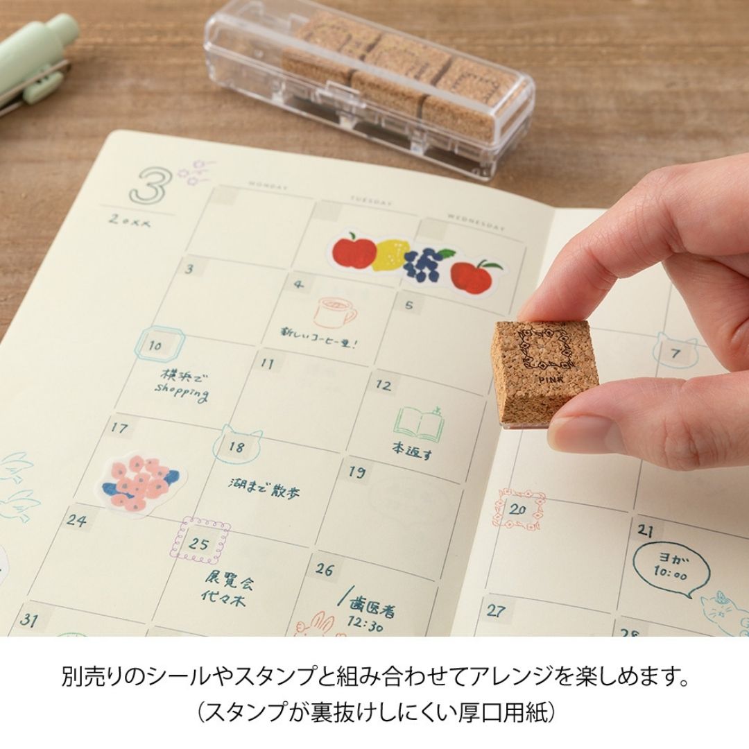 Small stamp being used on a calendar with colorful stamps in the background.