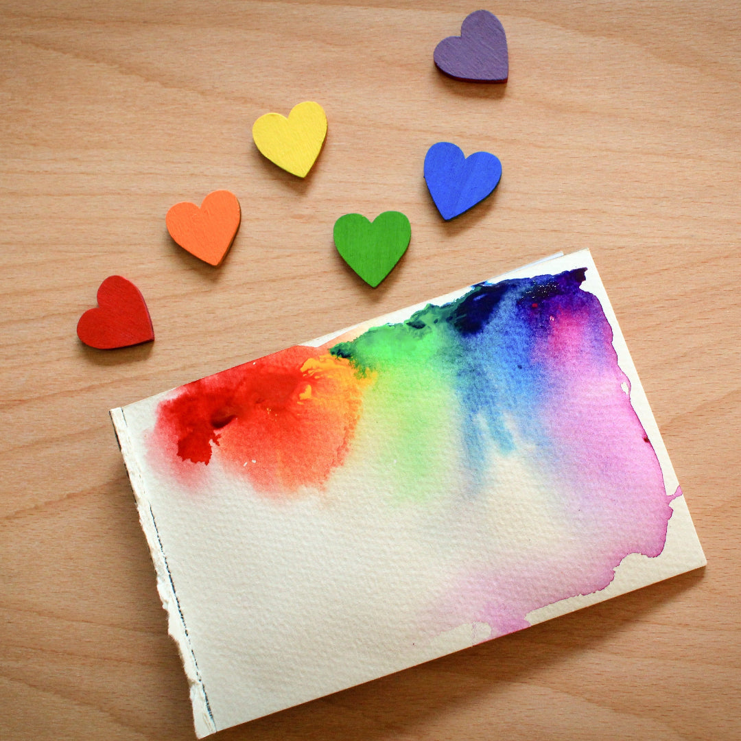 Colorful heart-shaped magnets on a wooden surface with a watercolor heart card.
